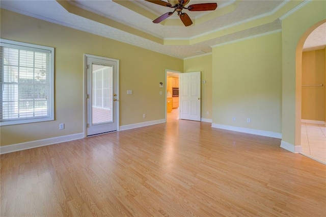 172 Lakeview Dr, Newborn, GA 30056 - spare room with arched walkways, a tray ceiling, a ceiling fan, ornamental molding, and light wood finished floors