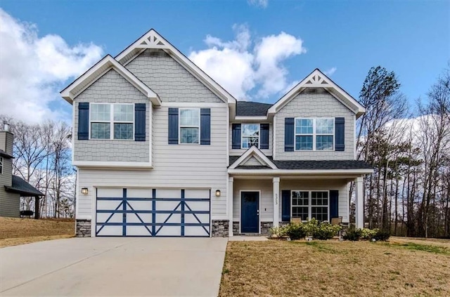 craftsman-style home with an attached garage, stone siding, a front lawn, and concrete driveway