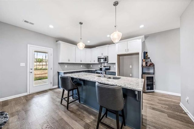 kitchen with visible vents, white cabinets, decorative backsplash, dark wood-style floors, and appliances with stainless steel finishes