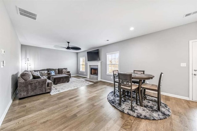 living room with baseboards, visible vents, a ceiling fan, wood finished floors, and a fireplace