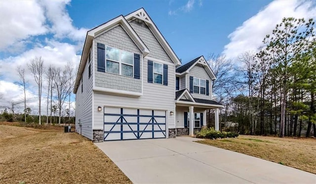 craftsman house featuring concrete driveway, stone siding, an attached garage, central air condition unit, and a front lawn