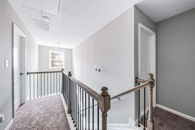 hallway with carpet floors, an upstairs landing, and attic access