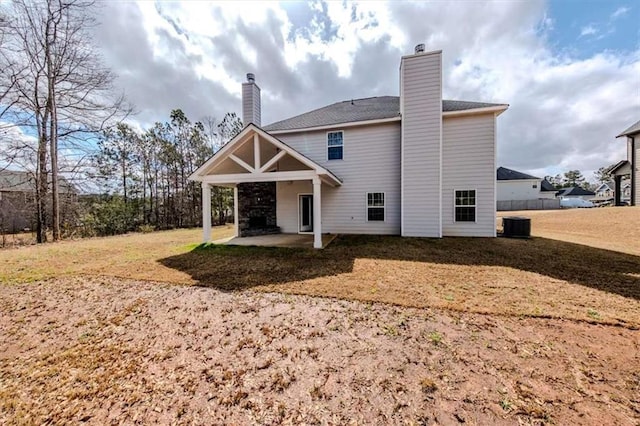 back of property featuring central AC, a patio area, a lawn, and a chimney