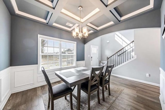 dining area with coffered ceiling, stairs, a chandelier, and dark wood finished floors