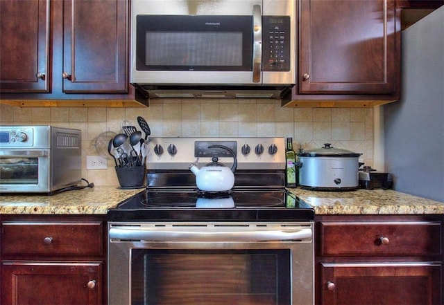 kitchen with tasteful backsplash, light stone counters, and stainless steel appliances