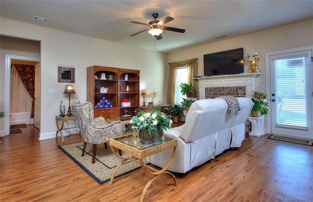 living room with ceiling fan, a fireplace, a healthy amount of sunlight, and hardwood / wood-style flooring