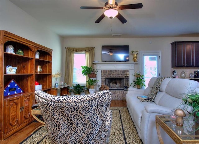 living room with hardwood / wood-style flooring, plenty of natural light, ceiling fan, and a brick fireplace