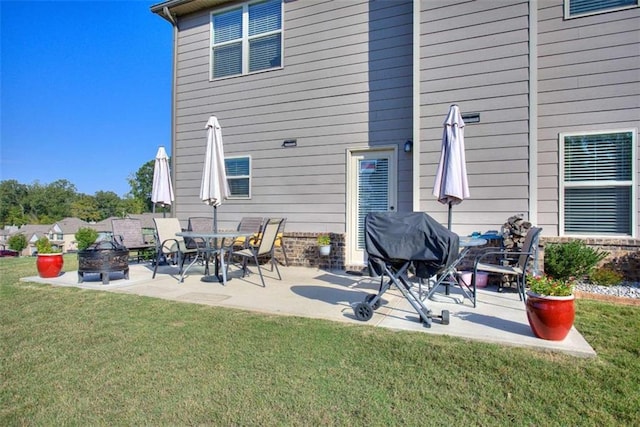 back of house with a lawn, a patio area, and a fire pit