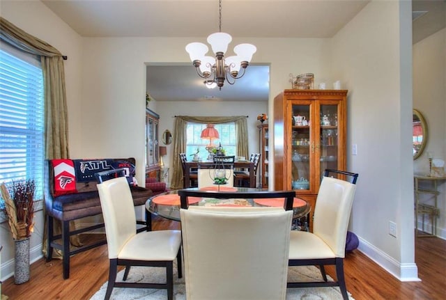 dining room featuring wood-type flooring and an inviting chandelier