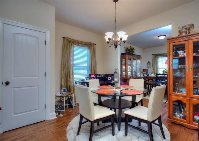 dining area featuring light hardwood / wood-style floors, a healthy amount of sunlight, and a chandelier