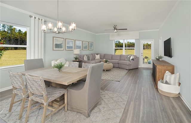 dining room with light wood-type flooring, ceiling fan with notable chandelier, and crown molding