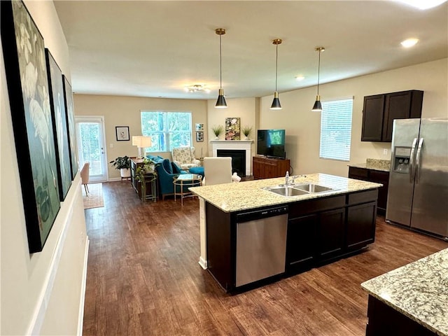 kitchen featuring sink, decorative light fixtures, dark brown cabinets, a center island with sink, and appliances with stainless steel finishes