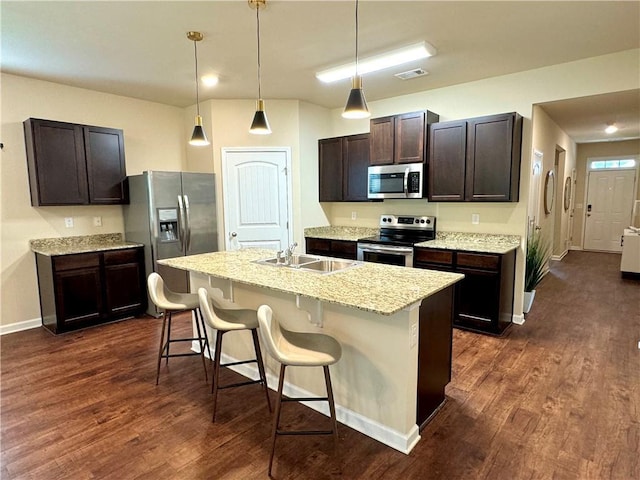 kitchen featuring dark hardwood / wood-style floors, an island with sink, a kitchen breakfast bar, dark brown cabinetry, and stainless steel appliances