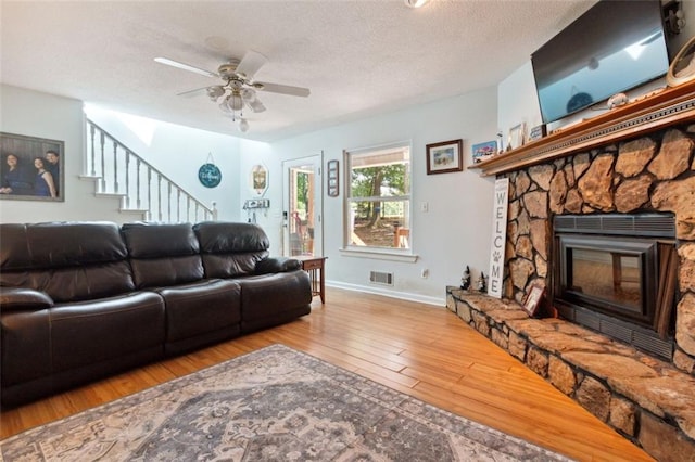 141 Mills Creek Path, Hiram, GA 30141 - living room featuring wood-type flooring, ceiling fan, stairs, a textured ceiling, and a stone fireplace