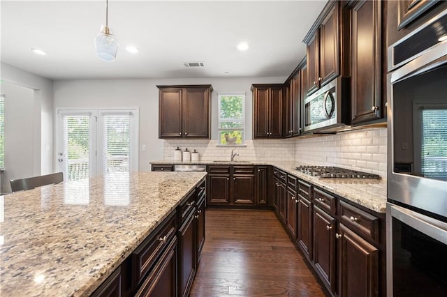 kitchen with visible vents, dark brown cabinets, dark wood-style floors, tasteful backsplash, and stainless steel appliances