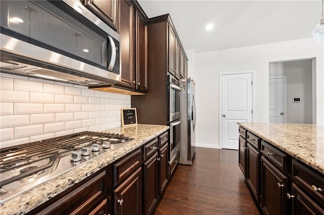 kitchen featuring backsplash, stainless steel appliances, dark wood finished floors, and light stone countertops