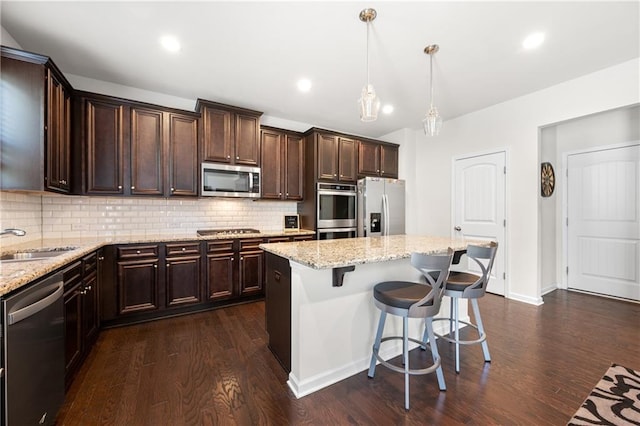 kitchen featuring appliances with stainless steel finishes, decorative backsplash, a sink, and dark wood finished floors
