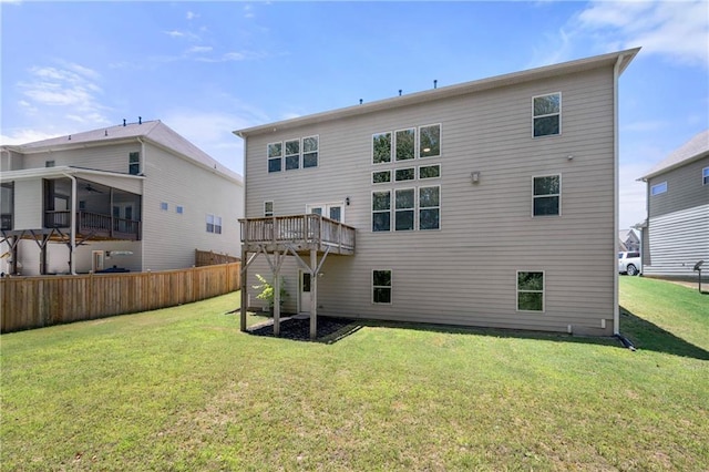 back of property with a lawn, fence, and a wooden deck
