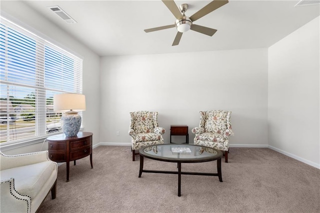 living area featuring carpet flooring, a ceiling fan, baseboards, and visible vents