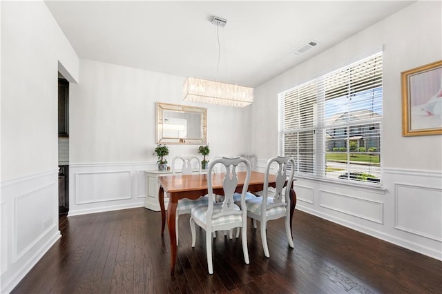 dining area featuring visible vents, a wainscoted wall, a chandelier, and dark wood-style floors