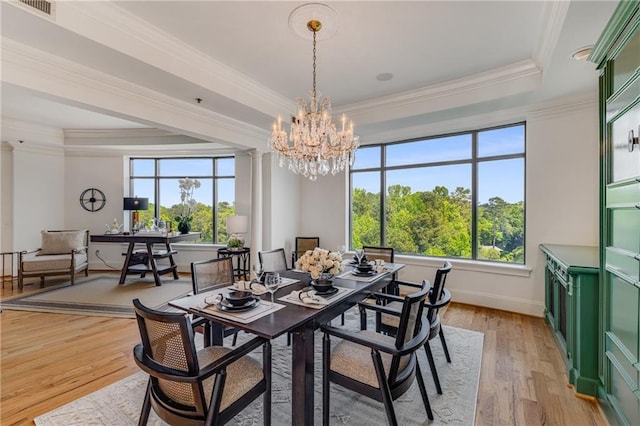 dining area with crown molding, a notable chandelier, light wood-style flooring, and a raised ceiling