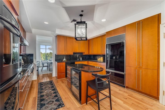 kitchen featuring brown cabinets, light wood-style floors, beverage cooler, tasteful backsplash, and high end black refrigerator