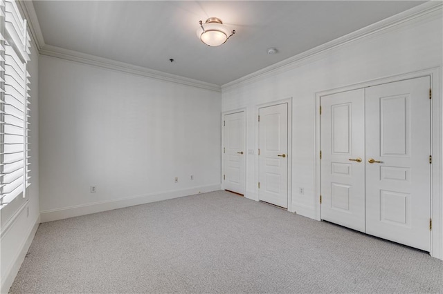 unfurnished bedroom featuring crown molding, baseboards, carpet, and two closets