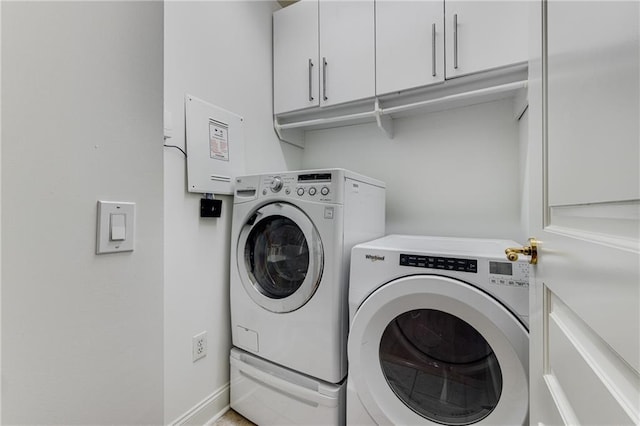 clothes washing area with separate washer and dryer, cabinet space, and baseboards