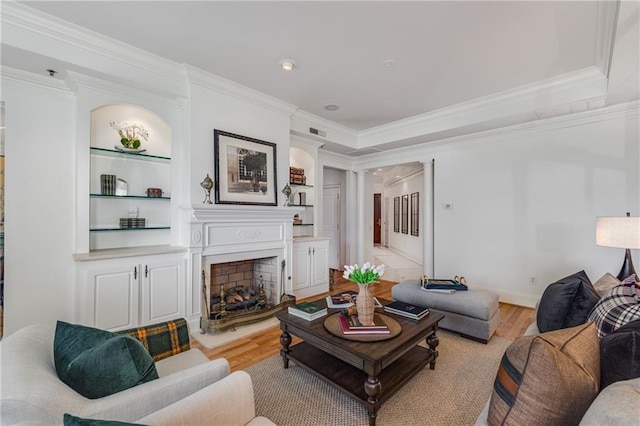 living room with crown molding, a fireplace with raised hearth, light wood-type flooring, and visible vents