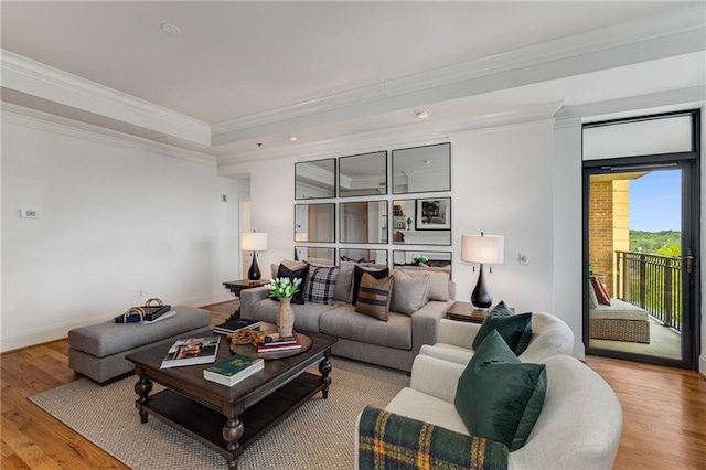 living room featuring crown molding, baseboards, recessed lighting, a tray ceiling, and light wood-style flooring