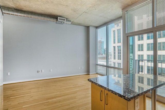 interior space featuring baseboards, light wood finished floors, and floor to ceiling windows