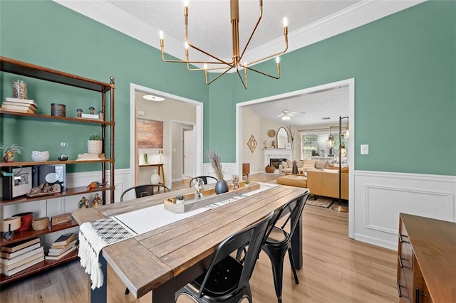 1865 Morgans Run Trl, Buford, GA 30519 - dining area featuring a wainscoted wall, a chandelier, light wood-style floors, a fireplace, and a textured ceiling