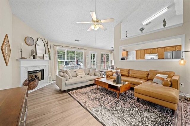 1865 Morgans Run Trl, Buford, GA 30519 - living room with a textured ceiling, lofted ceiling, light wood-style flooring, a ceiling fan, and a premium fireplace
