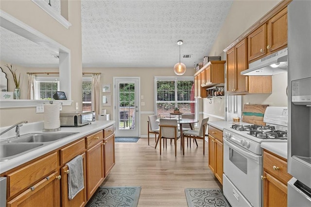1865 Morgans Run Trl, Buford, GA 30519 - kitchen featuring white range with gas stovetop, under cabinet range hood, a sink, a textured ceiling, and light countertops