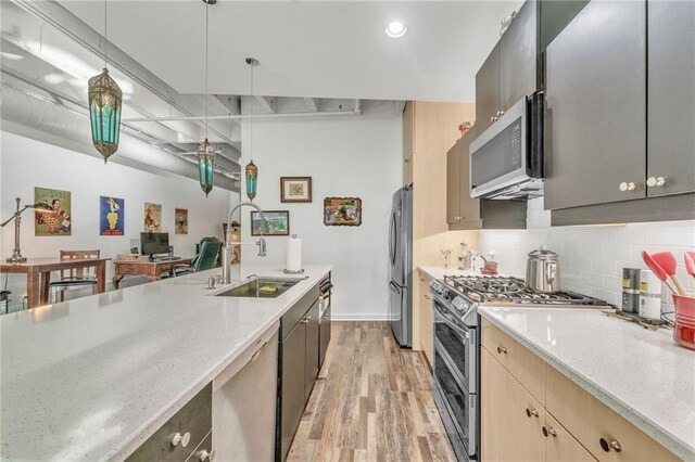 kitchen with sink, stainless steel appliances, pendant lighting, light hardwood / wood-style floors, and light brown cabinetry