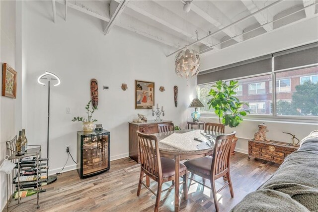 dining area with hardwood / wood-style flooring, a towering ceiling, and wine cooler