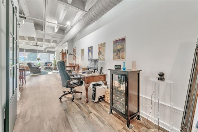 office with light wood-type flooring and ceiling fan