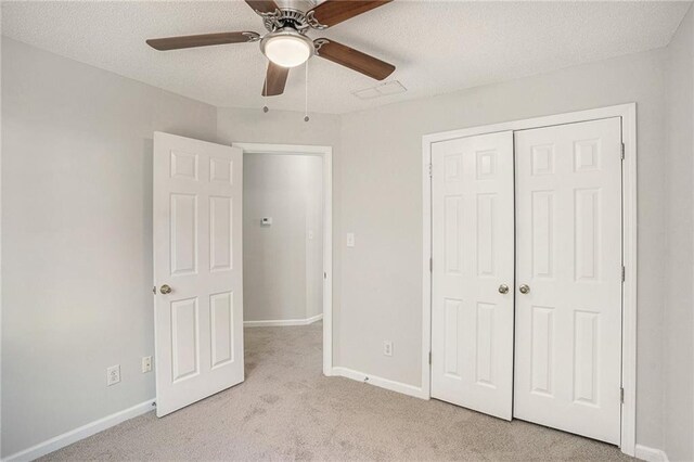 unfurnished bedroom featuring a textured ceiling, a closet, ceiling fan, and light colored carpet