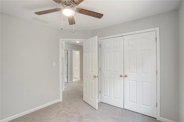 unfurnished bedroom featuring ceiling fan, light colored carpet, and a closet