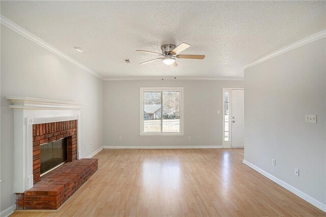 unfurnished living room with a brick fireplace, ceiling fan, ornamental molding, a textured ceiling, and light hardwood / wood-style floors