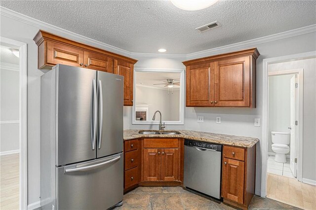 kitchen featuring sink, light stone countertops, a textured ceiling, ornamental molding, and appliances with stainless steel finishes