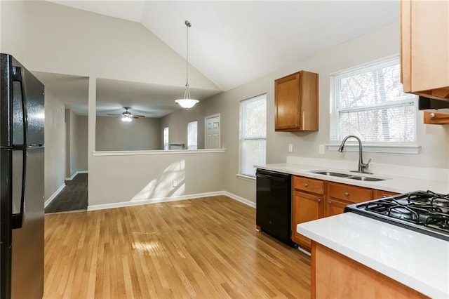 kitchen featuring black appliances, hanging light fixtures, light wood-type flooring, sink, and lofted ceiling