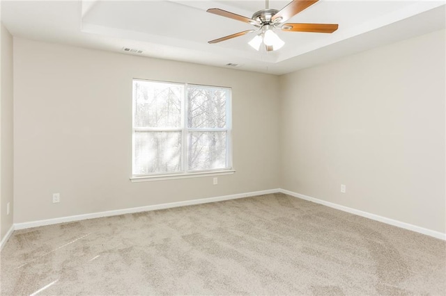 carpeted spare room with ceiling fan and a tray ceiling