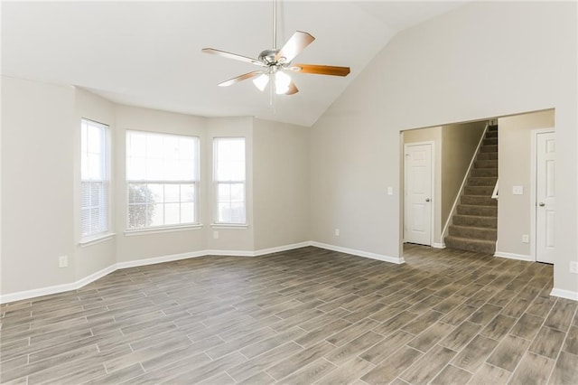 empty room with ceiling fan, hardwood / wood-style floors, and lofted ceiling