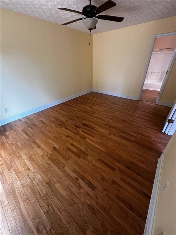 5026 Limerick Ln, Flowery Branch, GA 30542 - empty room featuring a textured ceiling, a ceiling fan, and dark wood finished floors