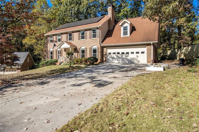 colonial home with a garage and a front lawn