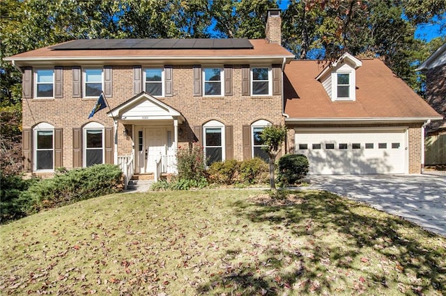 colonial home featuring a front yard and a garage