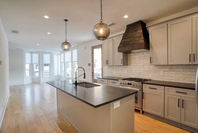 kitchen with custom range hood, a sink, dark countertops, decorative backsplash, and gas range