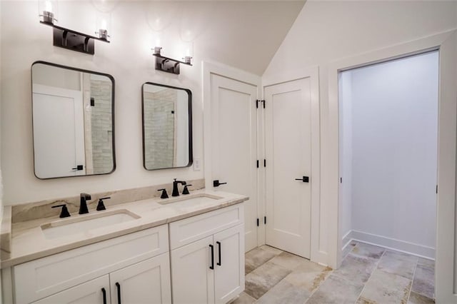 full bath with double vanity, vaulted ceiling, and a sink