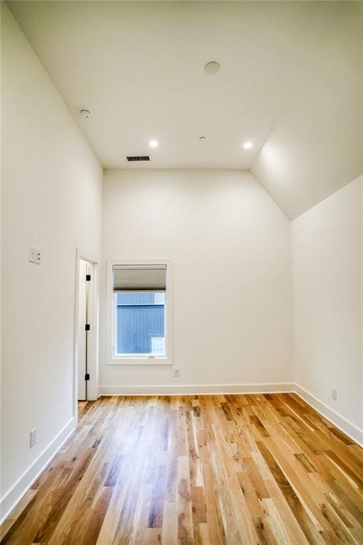 unfurnished room with lofted ceiling, wood finished floors, baseboards, and visible vents